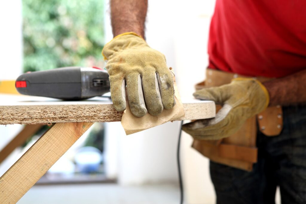 A worker sanding a shelf
