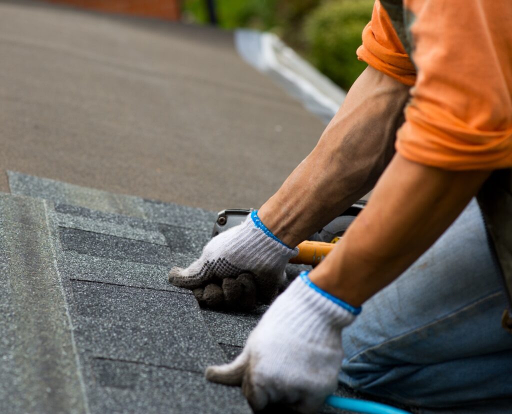 A roofer applies shingles to a roof