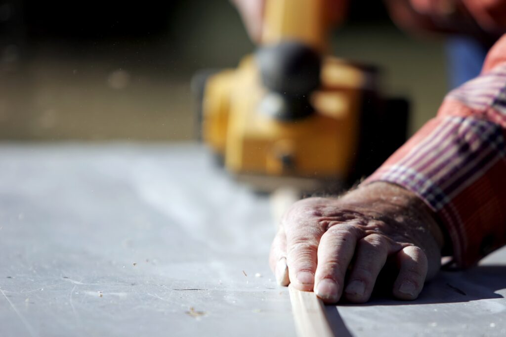 A construction worker planes a wooden trim piece